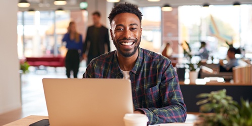 Man smiling while working on laptop in office