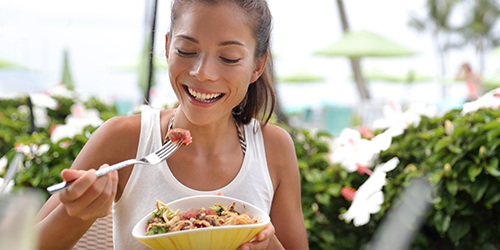 Smiling woman eating healthy meal outside