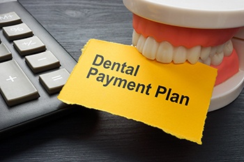 Artificial teeth biting yellow “Dental Payment Plan” paper