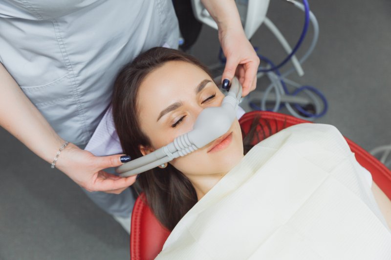 A woman receiving laughing gas through a nose mask